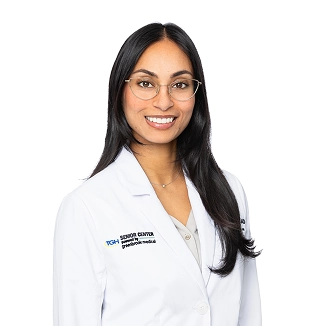 Dr. Anjali Sharma, a physician at PGMH Senior Center, smiles in a lab coat.