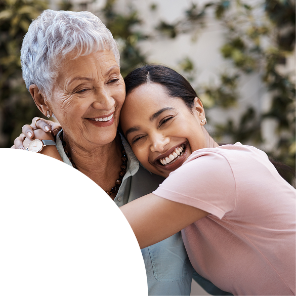 Senior woman and younger family member sharing a warm embrace and joyful smiles outdoors